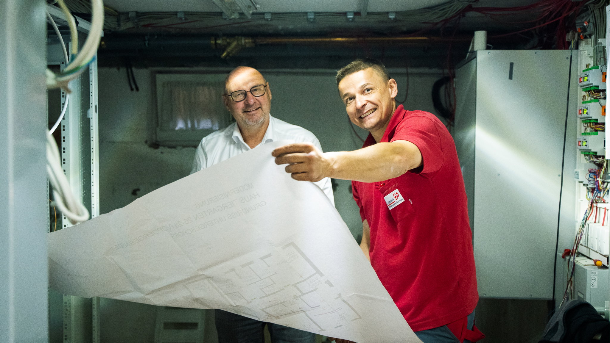 Zwei Kollegen begutachten und besprechen Baupläne in einer Werkstatt oder auf der Baustelle.
