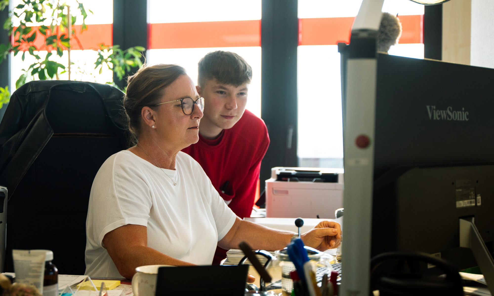 Eine Frau und ein junger Mann arbeiten konzentriert an ihren Computern im Büro.