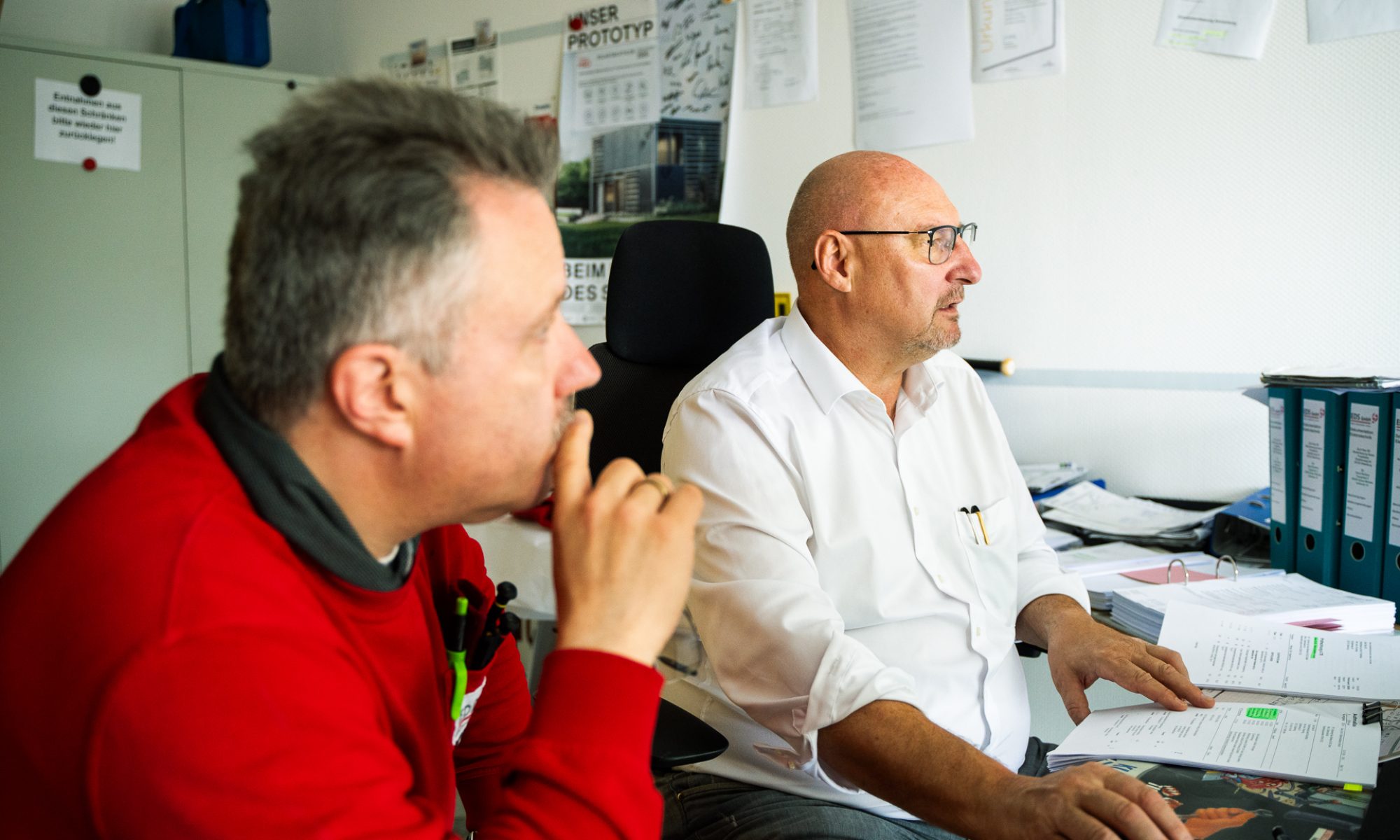 Zwei erfahrene Führungskräfte beraten sich in einem Büro über strategische Entscheidungen.
