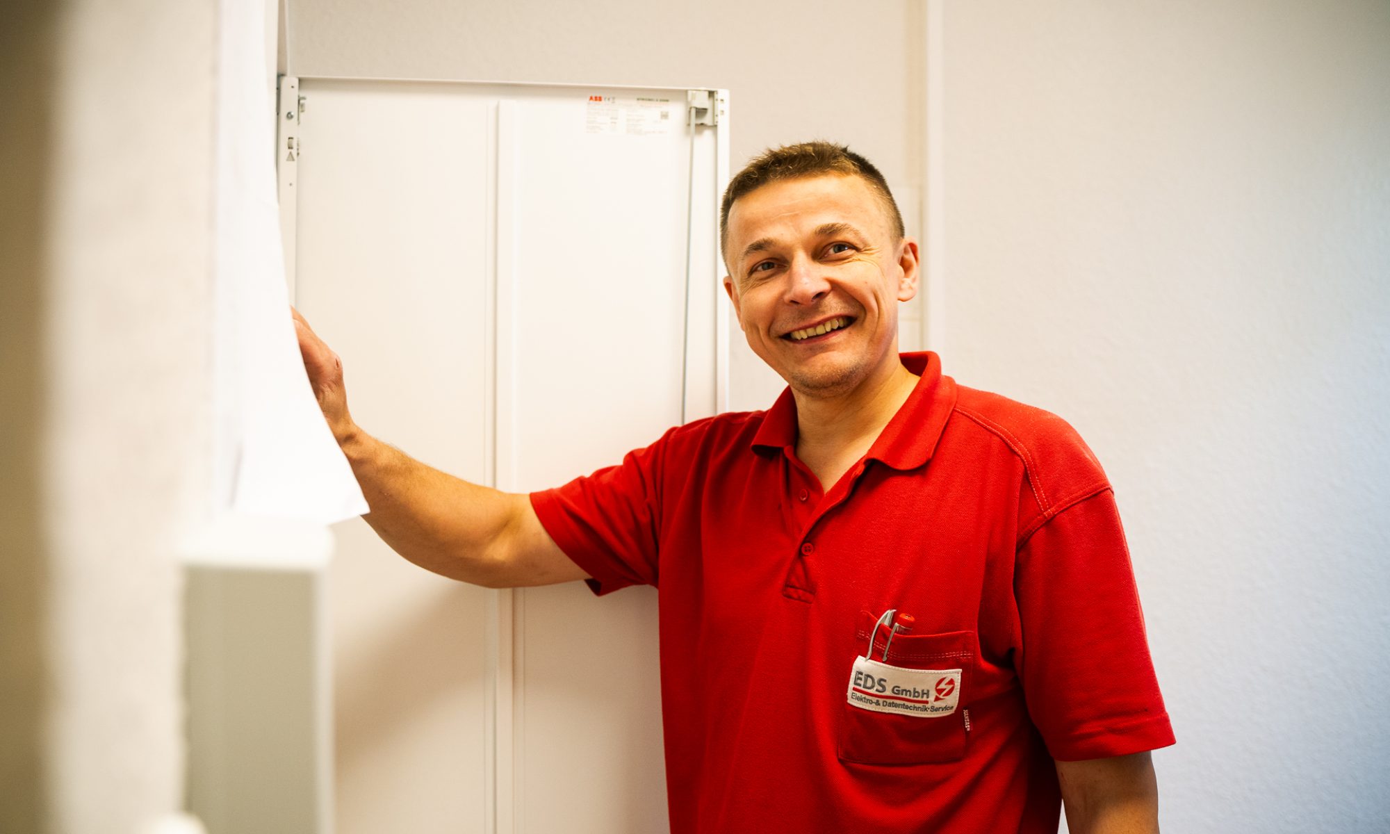 Ein stolzer Handwerker in rotem Poloshirt präsentiert sein fertig montiertes Werkstück.